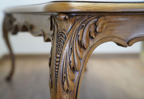 Carved wooden table detail with leaf and bead ornament, crafted from dark polished wood in a classic style.