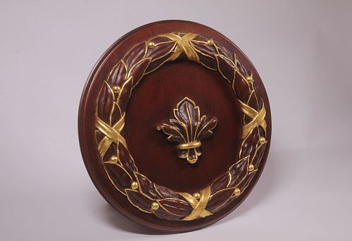Round wooden relief with carved laurel wreath and central element in the form of a golden lily, executed in the technique of artistic stucco.