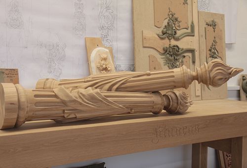 Carved wooden columns with intricate patterns lying on a workbench in the workshop