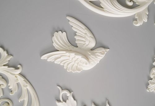 Polyurethane decorative element in the shape of a flying bird on a gray wall