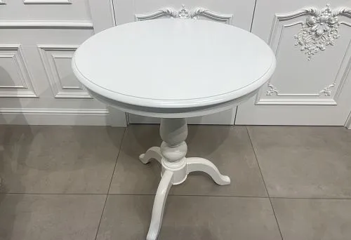Round wooden table with white countertop and carved leg in classic style.