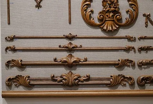 Carved wooden decorative elements of various lengths and shapes, neatly arranged on a stand, showcasing the richness of textures and styles.