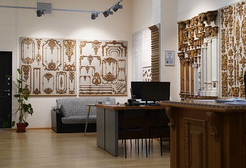 Showroom interior with samples of wooden carved decoration on walls, furniture, and work desks