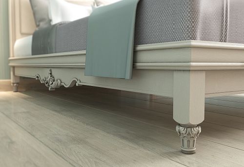 Lower part of the bed with carved decoration on legs in a light interior