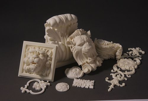 Reliefs and decorative elements from stucco: lion mascarons, capitals, rosettes and ornamental inserts on a dark background.