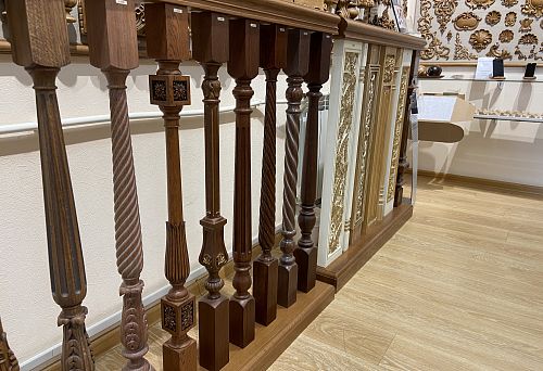 Photos of wooden balustrades and columns with various carved elements and decorative panels, located in an exhibition hall with wooden floors and walls adorned with ornaments.