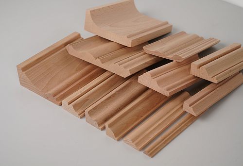 Various samples of beech wooden profiles, neatly stacked in piles.