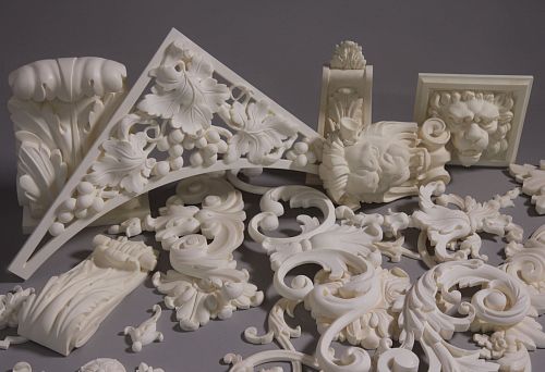 Set of decorative molding elements in classic style: scrolls, leaves, lion masks, and architectural forms, in light tones.