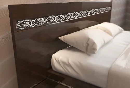 Fragment of a solid wood bed with a carved handcrafted ornament on the headboard