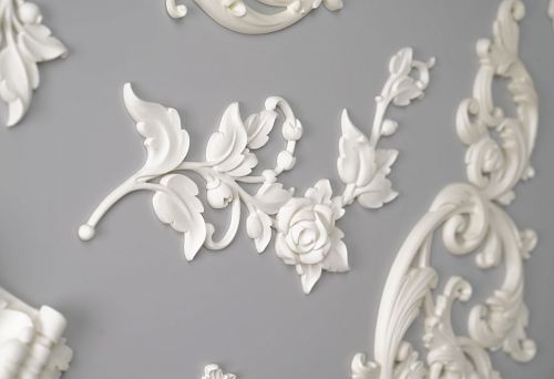 Fragment of polyurethane relief decor with floral ornament on gray background