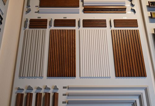 Collection of wall decorative panels and moldings in various shades and profiles, displayed on the stand.