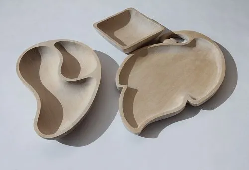 Set of wooden tableware made of natural wood with elegant shapes and various sections for serving dishes.