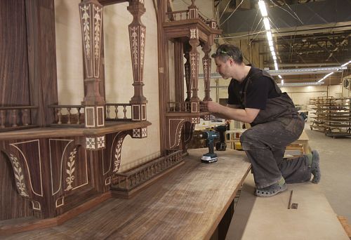 The craftsman is working on making a complex wooden item with decorative inlay