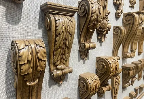 A row of decorative wooden brackets and consoles with carved patterns, designed for mounting shelves.