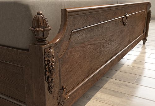Lower part of a classic dark wood bed with intricate carved decoration in the form of grape clusters and leaves