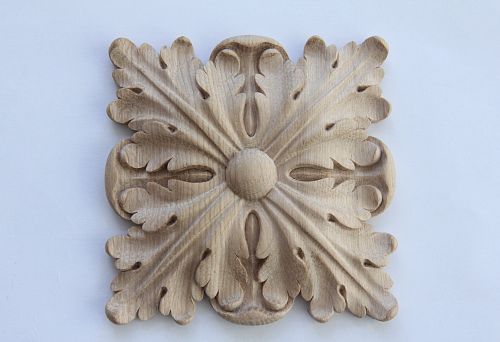 Wooden carved decoration element with a classic leaf ornament on a light background,