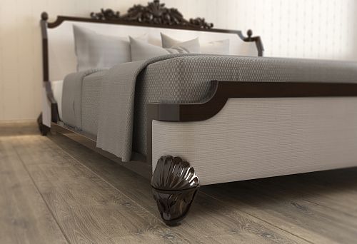 Wooden bed with dark headboard and carved elements on legs