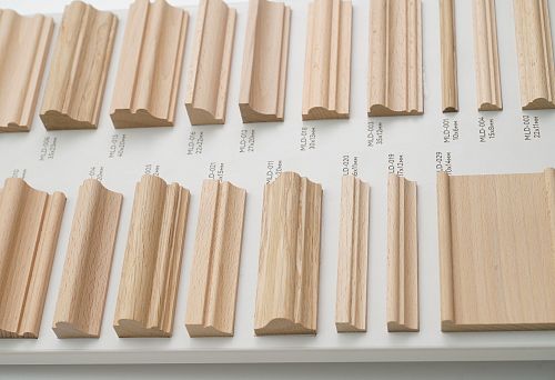 Samples of decorative wooden planks in various shapes and sizes on display, marked with profiles and cross-sections
