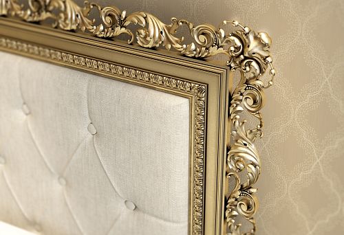 Luxurious wooden bed with carved golden decor on the headboard, styled in classic design against elegant wallpaper.