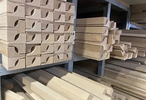Thin wooden dowels and decorative turned pieces neatly stacked on warehouse shelves