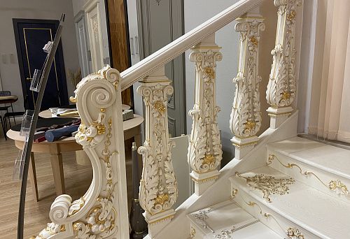 Luxurious white balustrade with gold elements and carved ornament
