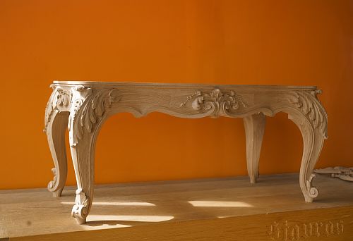 Wooden base with rich carving and curved legs against a bright orange wall, handmade, classic style