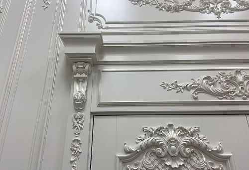 Белоснежное декоративное обрамление дверного проёма с лепным декором и изящными архитектурными формами в классическом стиле интерьера
