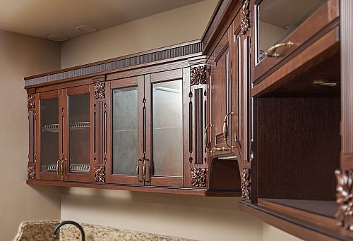 Classic kitchen cabinets with carved wooden fronts, glass inserts, and metal hardware