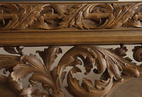 Carved oak ornament with large scrolls and leaf elements, coated with protective oil, in interior.