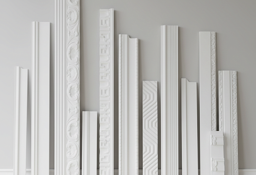 Разнообразие плинтусов из полистирола разных размеров и форм, представленных у стены, для выбора подходящего дизайна интерьера