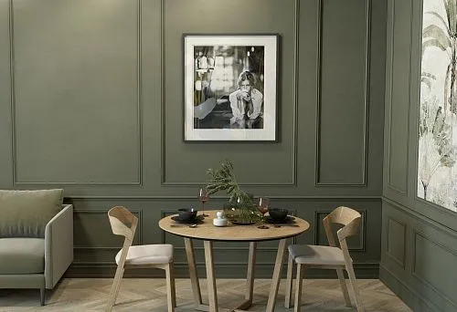 Round solid wood table with designer chairs in an elegant green interior