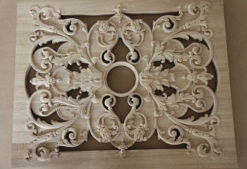 A hand-carved oak element with elegant botanical motifs and smooth lines, set against natural wood.