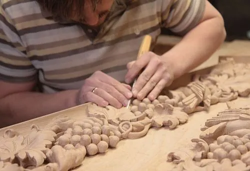 A craftsman carefully carves a decorative pattern on a wooden blank