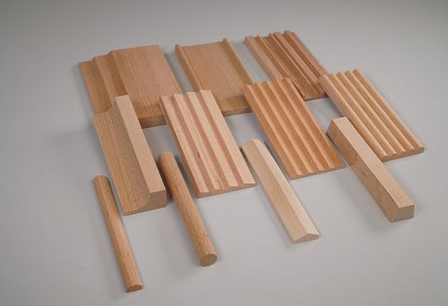 Set of wooden battens of different cross-sections and profiles on a gray background