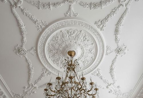 Snow-white ceiling medallion for chandelier with a round rosette and decorative ornaments in classic style