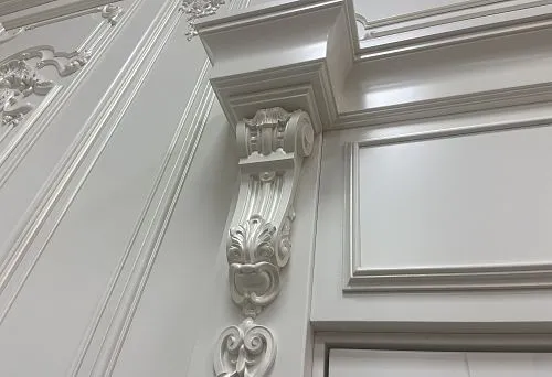 White decorative molding and pilaster from polyurethane on a wall with an elegant ornament
