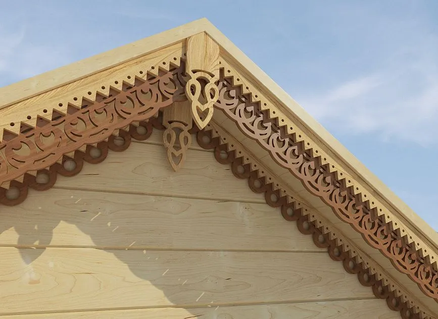 Carved wooden elements of the cornice and facade of a house with symmetrical pattern, made from natural wood.