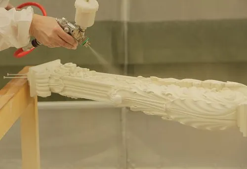 Процесс покраски резного лестничного столба с использованием распылителя